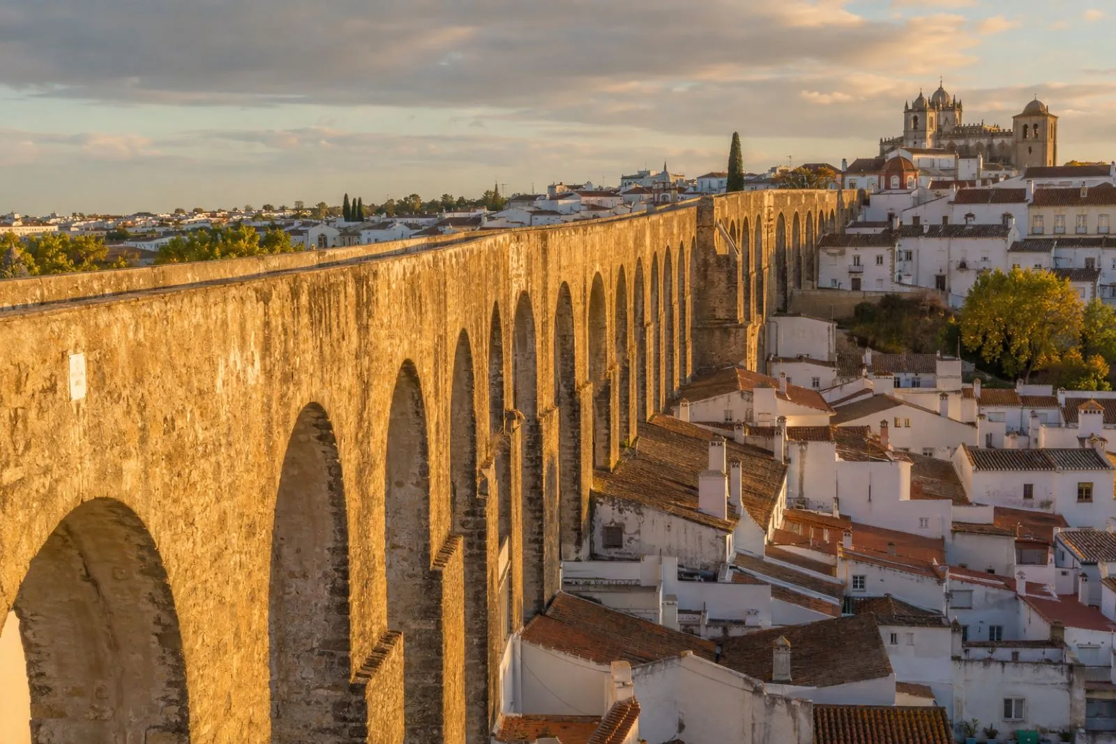 Evora aqueduct arches running into white houses